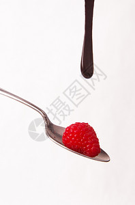 汤匙上沾着巧克力糖浆的草莓图片