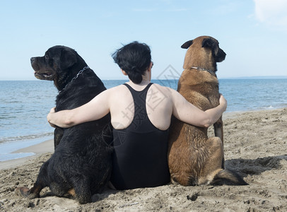 年轻女子和她的狗在海滩上图片