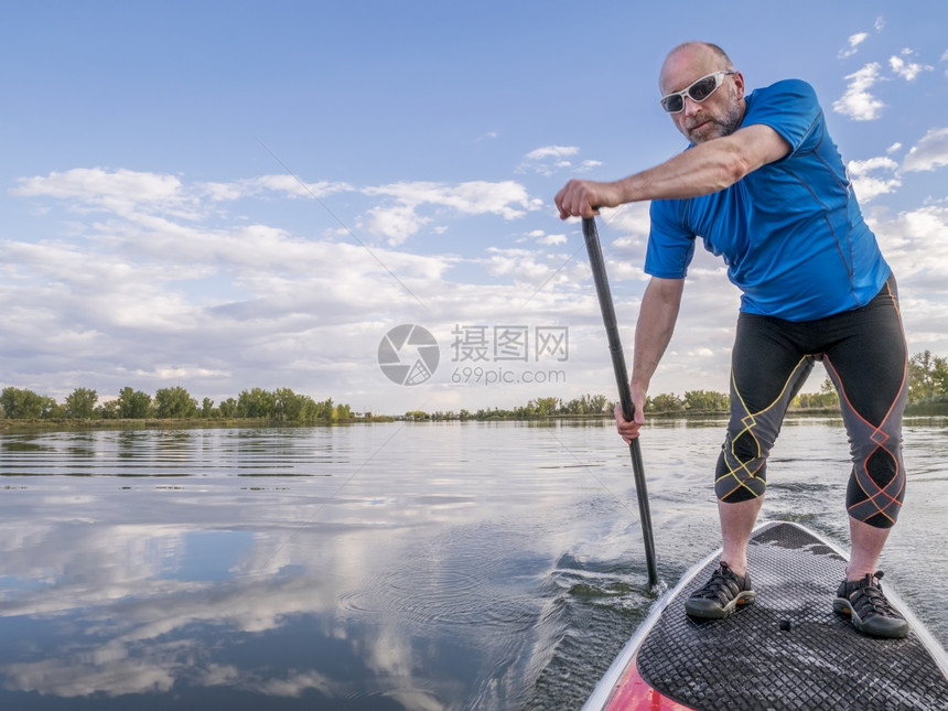 在科罗拉多州平静湖夏末的悬浮板SUP上享受锻炼的高级男护板图片