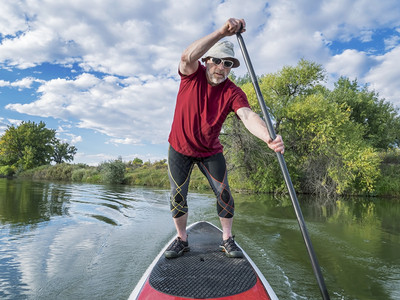 在科罗拉多州平静湖夏末的悬浮板SUP上享受锻炼的高级男护板图片