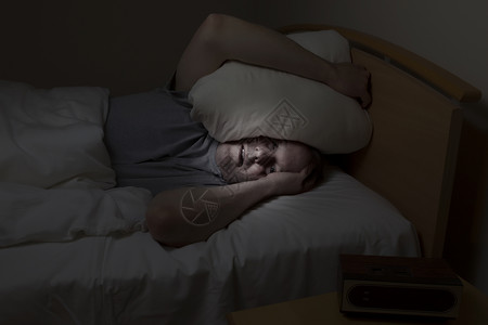 成年男子头顶枕头眼睛睁大失眠无法入睡图片