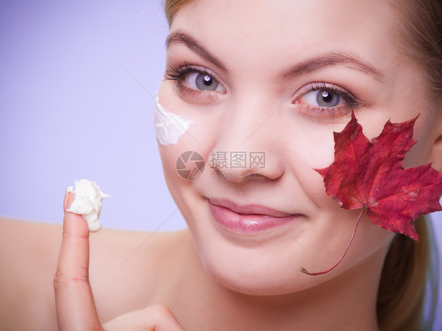 皮肤习惯年轻女面孔灰色上以叶子作为红毛皮的标志女孩用湿润奶油照顾干燥的皮肤美容治疗图片