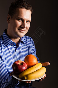 快乐的年轻人在黑暗灰色上拿着水果一群建议健康营养的人图片