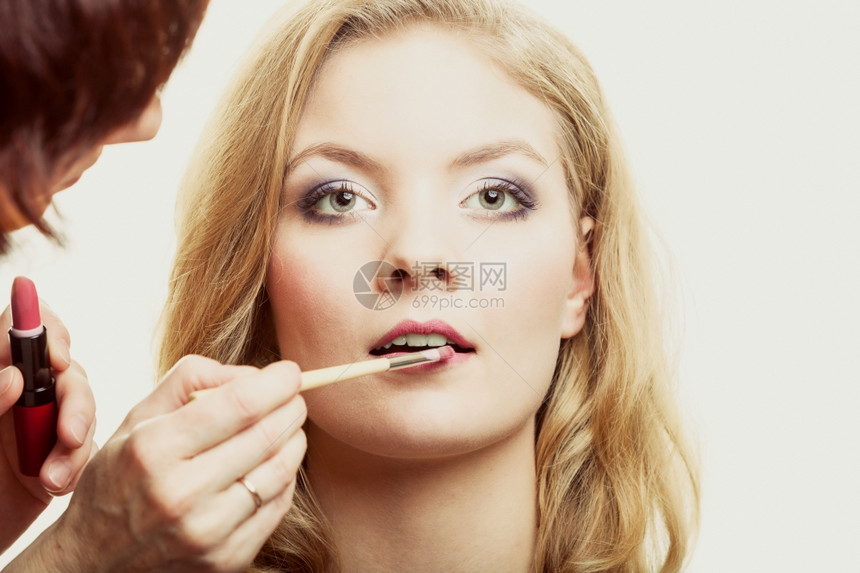化妆师将口红和配件工具应用到女嘴唇上图片