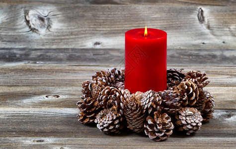 在真正的松果花圈里明亮的红蜡烛里圣诞节的花圈里在生锈的木板上图片