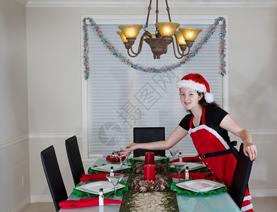 年轻少女穿着圣诞老人服装为节假日安排餐厅桌背景图片