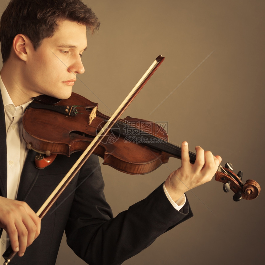 年轻优雅的小提琴家手在棕色和古典音乐上拉小提琴图片