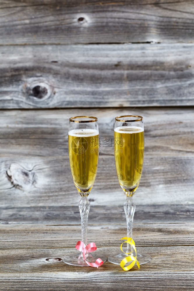 金香槟的垂直形象以优雅的眼镜挂在有丝带的生锈木上图片
