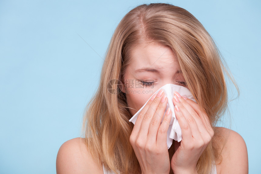 流感或过敏症状生病的年轻女孩在蓝色组织里打喷嚏保健工作室拍到图片
