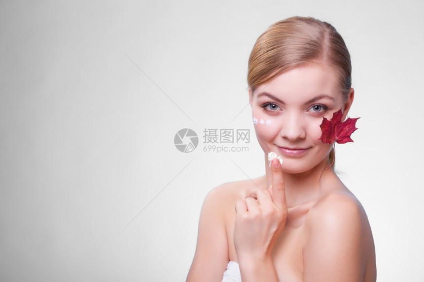 皮肤习惯年轻女面孔灰色上以叶子作为红毛皮的标志女孩用湿润奶油照顾干燥的皮肤美容治疗图片