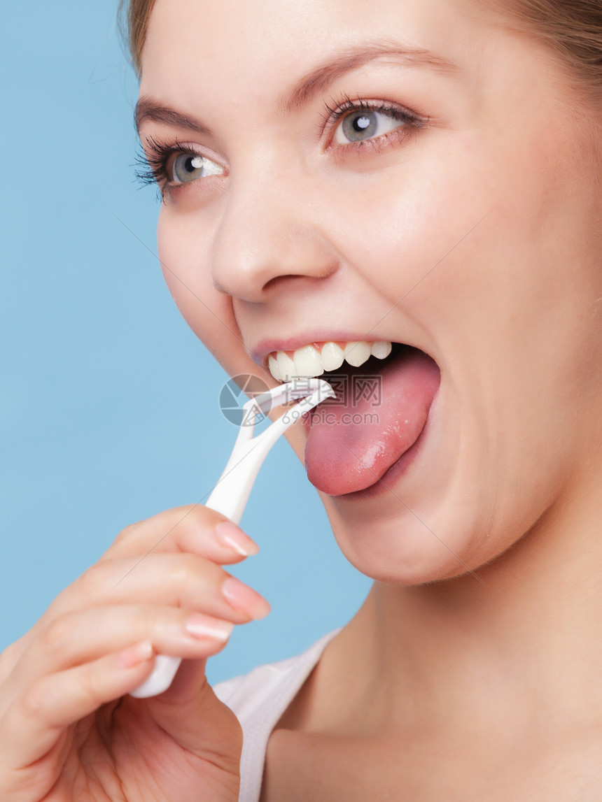 年轻女孩微笑用蓝色的清扫舌头每日牙科护理和口腔卫生工作室拍摄图片