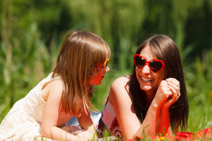 母亲和女儿戴着心脏塑造的太阳镜在公园户外野餐图片
