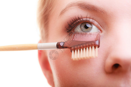 装饰美容程序和化妆概念关闭女部分面化妆细节使用梳子在应mascara之后分别抽鞭子长的睫毛背景图片