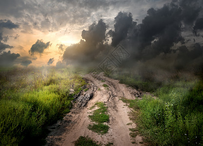 云污垢日落时乡间公路上有雾和泥土背景