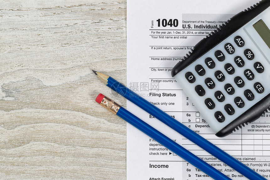 美国税务表104木制桌面上的计算器和铅笔图片