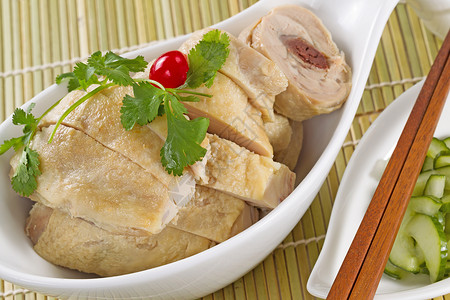 白碗中的国切片烤鸡配有黄瓜作为天然竹子垫下的边盘菜图片