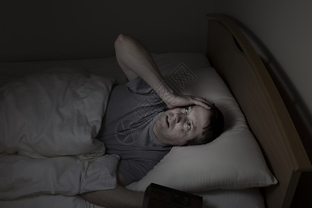 成熟的男子仰天顶无法在夜里睡着因为失眠背景图片