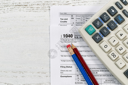 美国个人税表104的顶端视图木制桌面上有旧的计算器和铅笔图片
