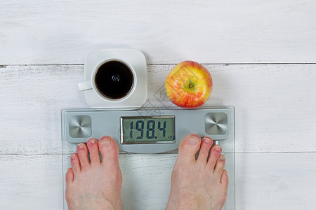 体重,显示赤性双脚和全苹果,白色木制地板前面黑咖啡图片