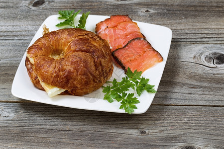 近距离的早餐包括新鲜烤面鸡蛋冷烟鲑鱼和欧斯利在生锈木板上图片