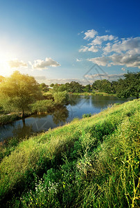 阳光照耀时在河流附近有青绿草的山丘图片