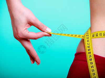 健康照顾和营养年轻身体健康的妇女适合孩用测量胶带她的腰围蓝色绿图片