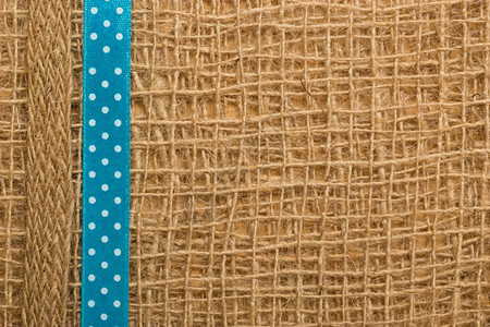 棕色网状材料天然薄膜背景上的Polka点蓝色丝带图片