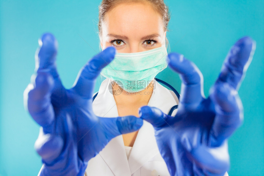 年轻女医生面对外科具和蓝底医疗手套图片