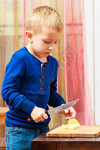 小男孩玩厨房刀切苹果在家里做沙拉图片