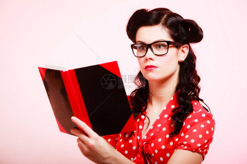 时髦的女学生或教师眼镜里的女学生或老师读着关于粉红色的书图片