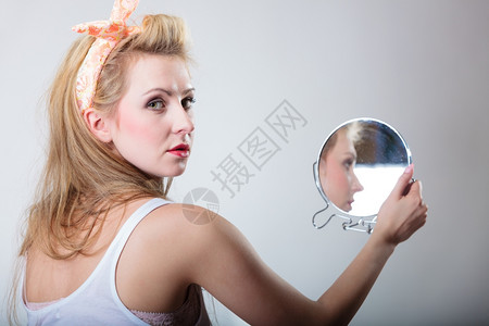 穿着发带的金美女时装郎看着镜子的倒影时装摄棚拍的灰色背景图片
