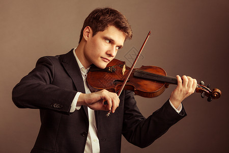 年轻优雅的小提琴家手在棕色古典音乐演播室拍小提琴背景图片