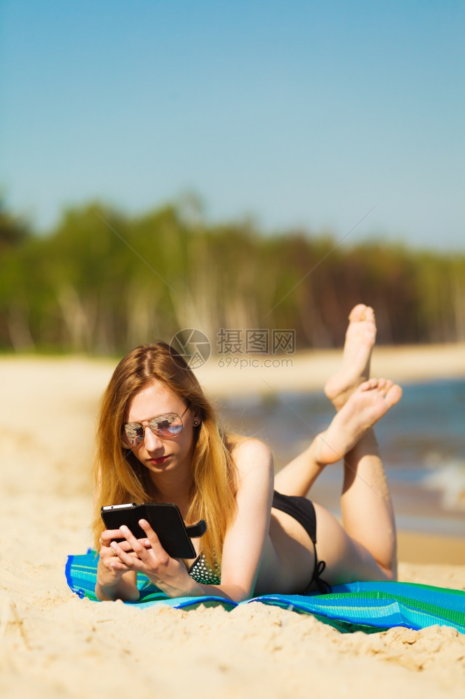 暑假比基尼日光浴的感女孩在海滩晒黑年轻女人在海边用手机放松夏天图片