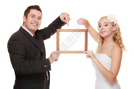 结婚日快乐的年轻夫妇指着照片的空框图片