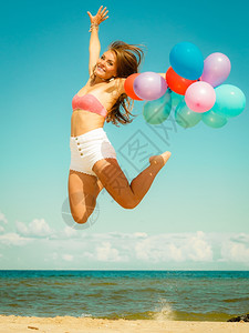 暑假庆祝活动和生方式概念美丽的少女孩在海滩上用彩色气球跳出海滩图片