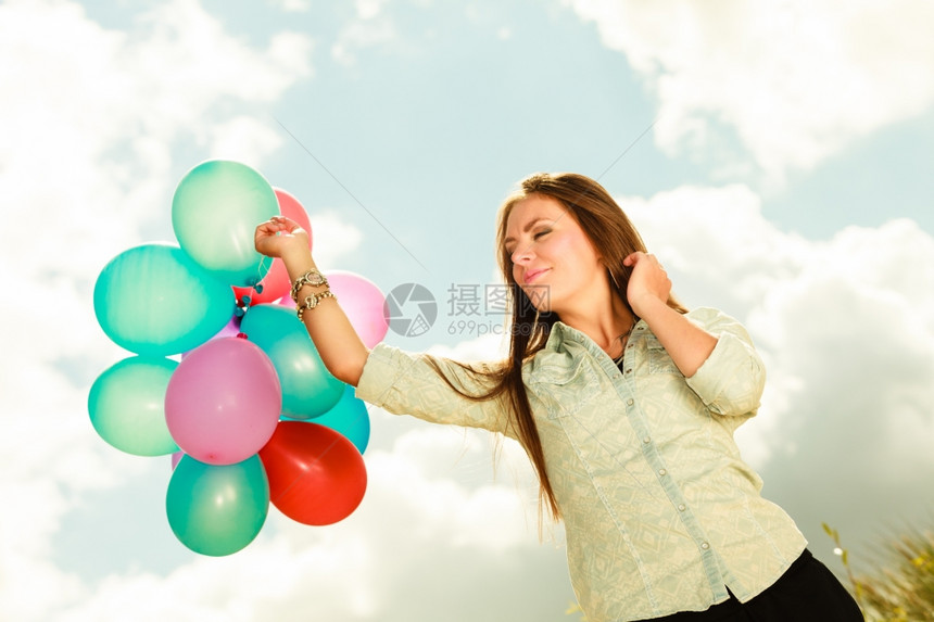 节日庆和生活方式概念具有吸引力的女模特在云层背景外持有一连串多彩气球图片
