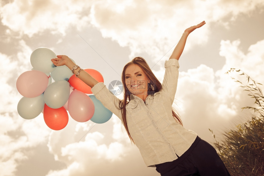 节日庆典和生活方式概念具有吸引力的女模特在云层背景之外持有一连串多彩气球图片