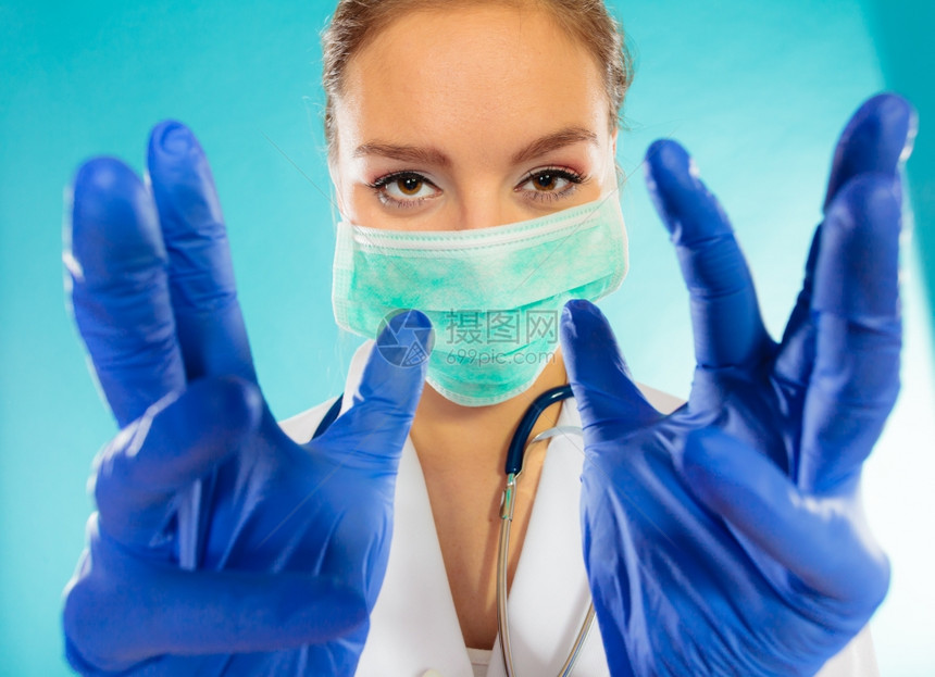 年轻女医生面对外科具和蓝底医疗手套图片