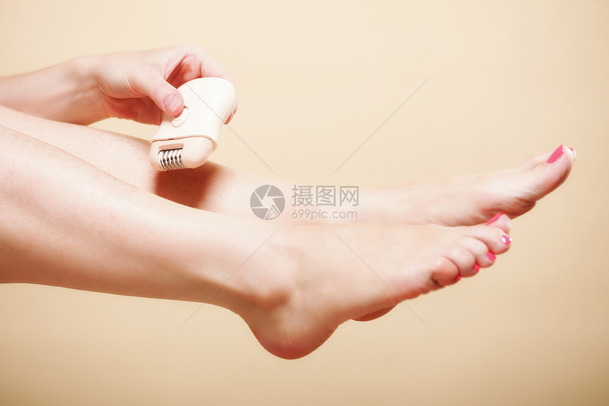 妇女用电剃须刀腿在橙子上刮落美容和皮肤护理概念图片