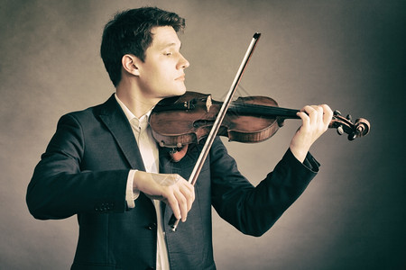 斯特拉迪瓦利乌斯年轻优雅的小提琴家手在棕色和古典音乐上拉小提琴背景