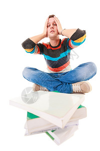 疲劳的大学生累得要死一堆书在为隔离考试而学习压力工作室中图片