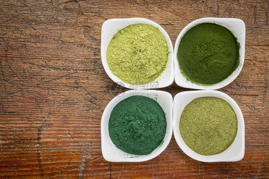 四种健康的绿色饮食补充粉松树氯小麦草和莫林加叶放在白碗中石灰木上图片