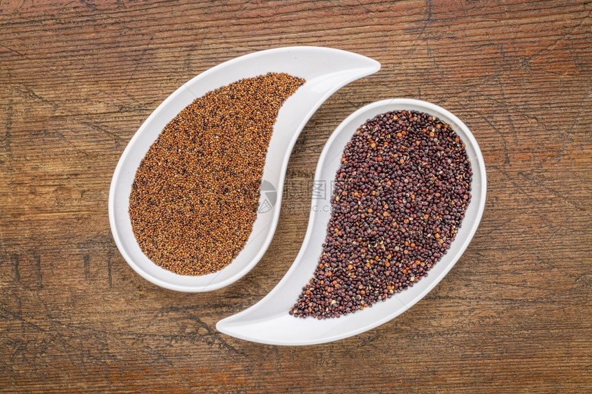 卡尼瓦和黑quinoa谷物在泪滴上成碗与生锈的木头对立图片