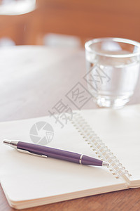 空白螺旋日记本上放着一支笔背景图片