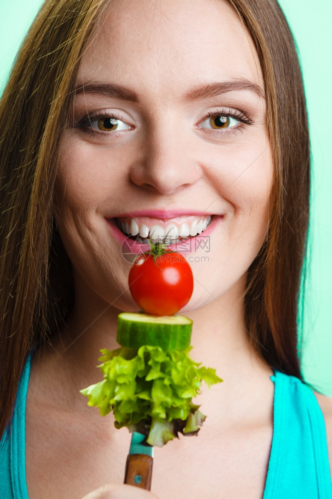 美食和减肥概念有趣的女孩健身人拿着叉子和新鲜混合蔬菜绿色蓝背景图片