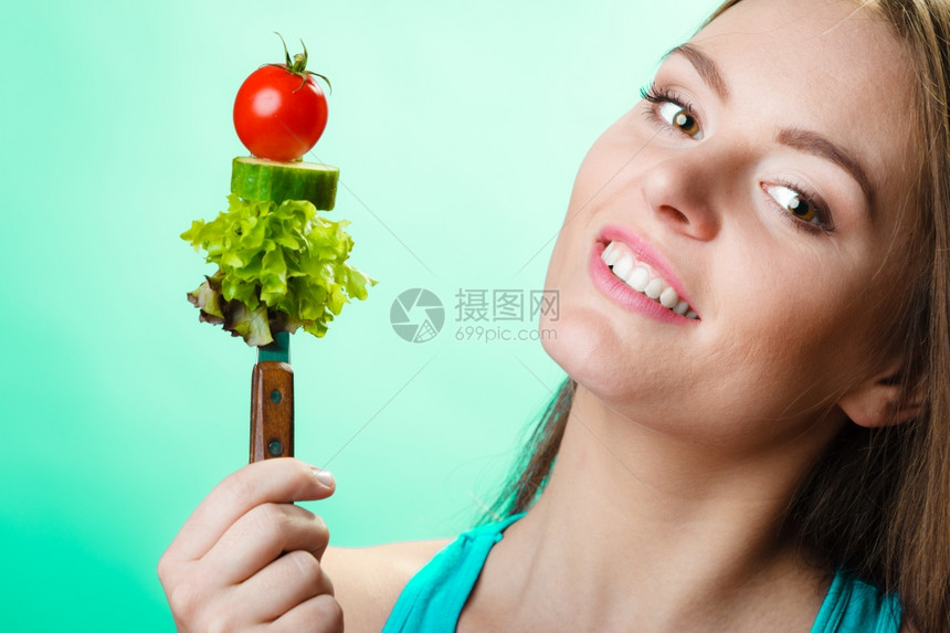 健康的饮食和概念快乐的年轻女子以绿色蓝背景拿着蔬菜工作室拍摄图片