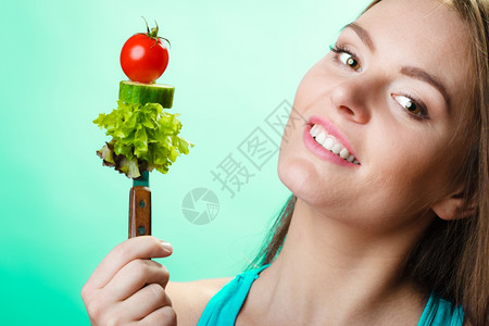健康的饮食和概念快乐的年轻女子以绿色蓝背景拿着蔬菜工作室拍摄图片