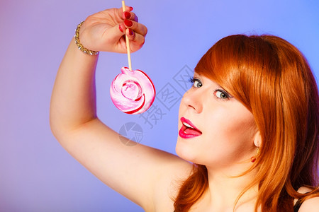 喜欢吃甜食漂亮的女孩拿着棒糖紫色和蓝背景的棒糖图片