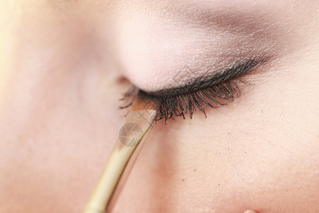 女人用刷子在眼睛上化妆图片