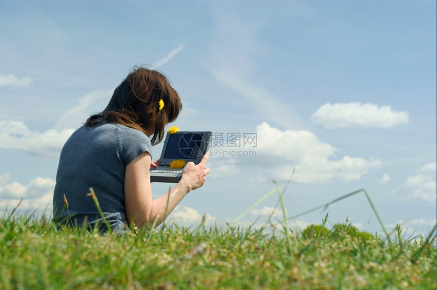 女人在草原外面的笔记本电脑上打字蓝天有云图片